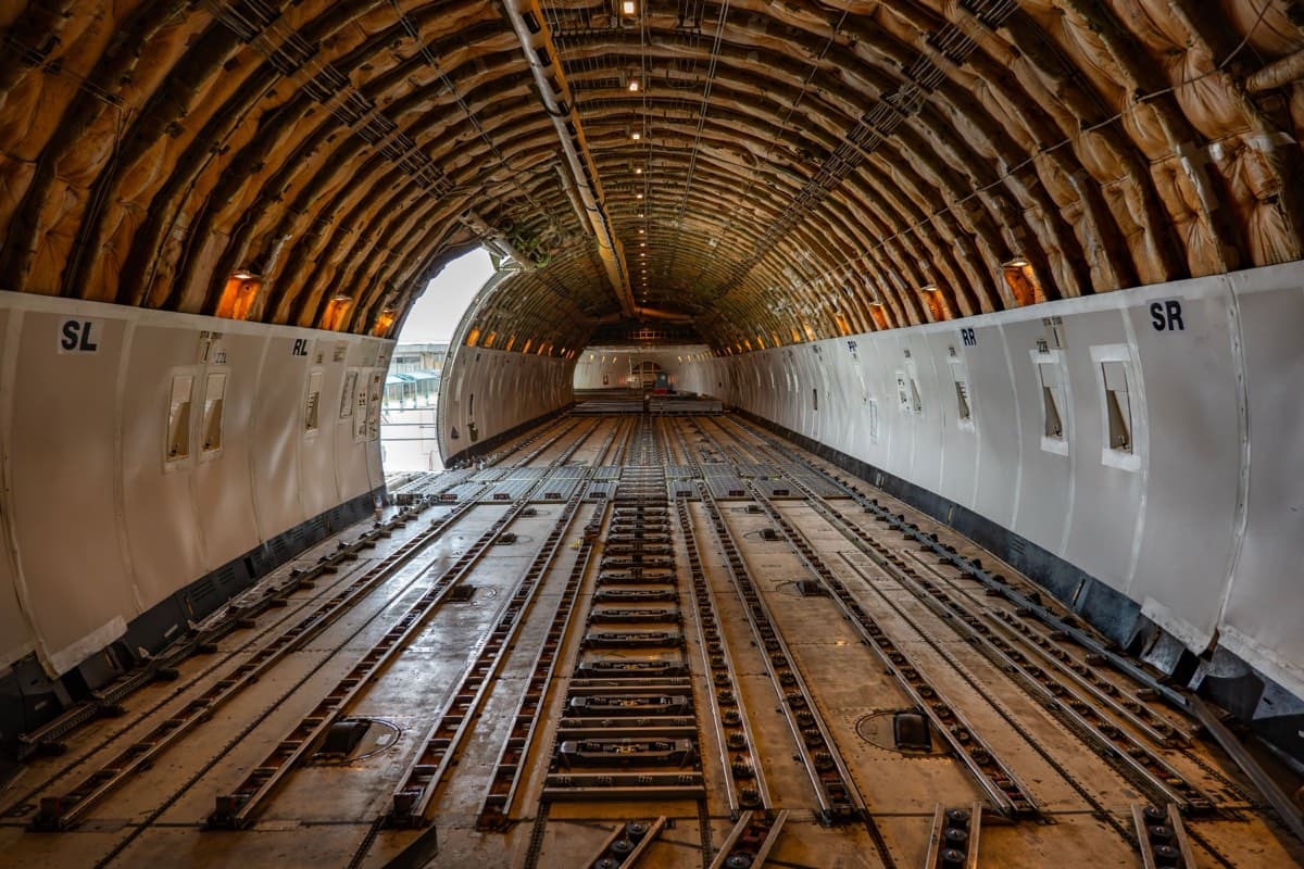 Interior of an empty aircraft cargo hold with roller tracks for pallet loading