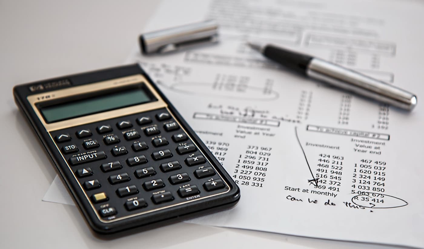 Close-up of a calculator and pen on a printed financial worksheet